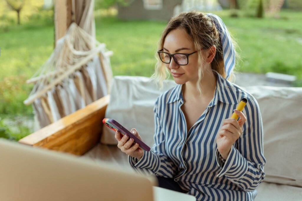 a beautiful girl smokes an electrode cigarette and uses a smartphone event organizer